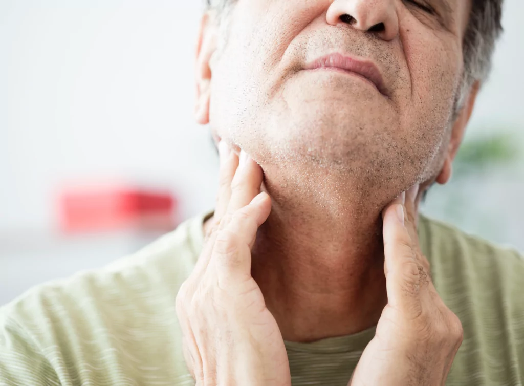 Man with throat cancer feeling his neck